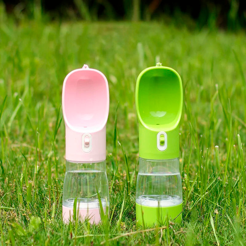 Two PetPal Water & Snack Bottles, one pink and one lime green, with flip-up spouts and transparent midsections, on grass.