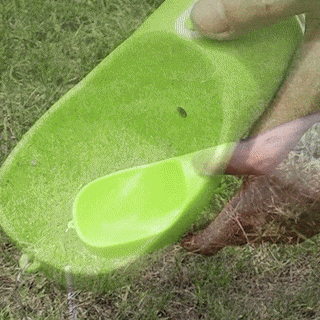 A person is holding a lime green PetPal Water & Snack Bottle with a scoop shape, pouring water into it for a dog to drink from.